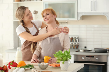 Wall Mural - Young woman and her mother cooking in kitchen