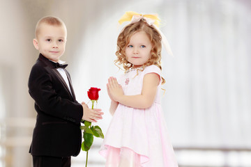 The boy gives the girl a flower.