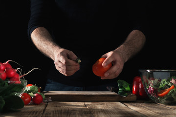 Canvas Print - Man preparing salad of fresh vegetables in home kitchen