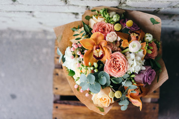 colorful bouquet of different fresh flowers against brick wall. bunch of orchids, roses, freesia and