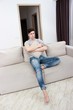 © Saksoni - Handsome young man holding remote control and looking bored while watching TV