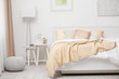 Comfortable bed with soft beige coverlet and pillows in light modern room