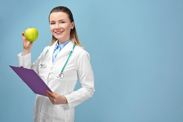 Wall Mural - Young female nutritionist on light color background