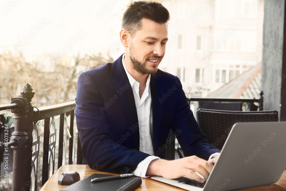 Young businessman working with laptop in outdoor cafe