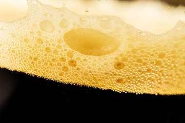 Beer foam close-up in a glass with dark beer