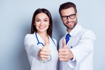 happy medic workers. portrait of two doctors in white coats and glasses showing thumb-up against whi