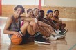 High school kids sitting indoors in basketball court