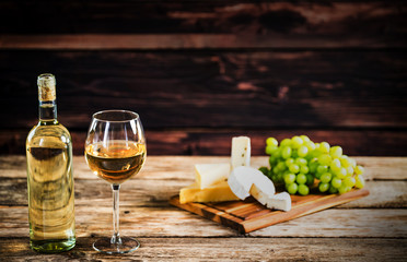 Wall Mural -  Wine bottles with grapes and cheese on wooden rustic background. copy space