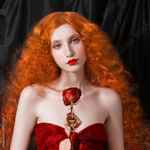 A Woman With Red Hair In A Red Fitting Long Dress With Dry Rose In