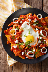 Wall Mural - Mexican breakfast: chilaquiles with egg and chicken close-up. Vertical top view