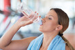 © FS-Stock - Fitness woman. Beautiful young girl in the gym drinking water, with blue towel.