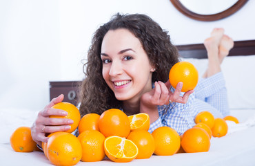 Wall Mural - Young brunette with ripe oranges in bed