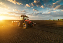 Farmer With Tractor Seeding - Sowing Crops At Agricultural Field In Spring