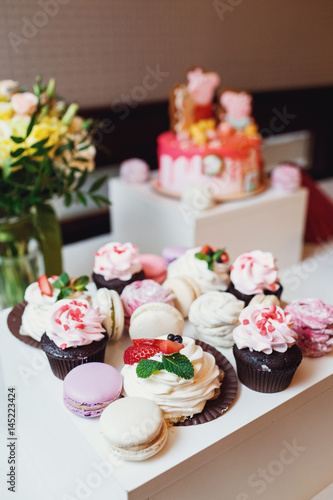 Fotografie, Tablou Tasty macaroons and cupcakes on white dinner table