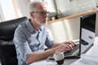 © thodonal - Portrait of senior businessman working on laptop, hard light