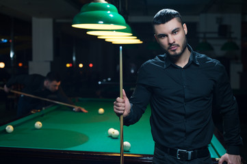 Male friends playing billiard game in club