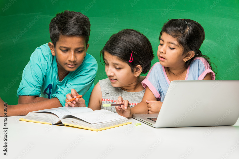 Kids Learning Computer R Indian indian school kids using laptop in a classroom over green chalkboard ...