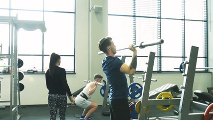 Wall Mural - Fit young men in gym working out, lifting barbells