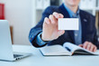 © cameravit - Businessman in suit and hand holding blank calling card. Male hand showing white visiting card in camera closeup. Partners contact information exchange concept. Introducing gesture at formal meeting