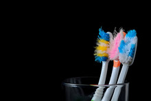 Old Used Toothbrushes In Glass On Black Background