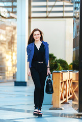 Happy young business woman outside and looking somewhere. Beautiful smiling woman.