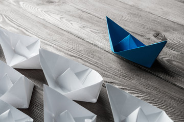 Business leadership concept with white and color paper boats on 