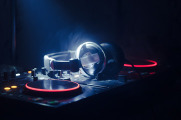 Wall Mural - DJ Spinning, Mixing, and Scratching in a Night Club, Hands of dj tweak various track controls on dj's deck, strobe lights and fog, selective focus, close up. Dj Music club life