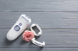 Modern epilator with accessories and flower on wooden background