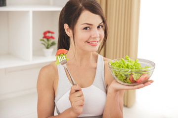 beautiful sporty woman eating a bowl of salad