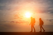 © Johnstocker - Silhouettes of two hikers with backpacks enjoying sunset. Travel concept.
