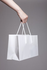 Wall Mural - woman hand hold a shopping paper bag, grey background.