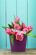 Happy Mother's day card with pink tulip bouquet in purple flower pot with blue wooden surface as background
