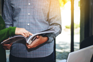 image of young  business man and his co worker are reading magazine  at office with burred of world globe background