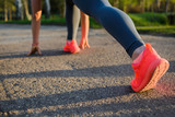 Fototapeta Sport - Runner feet running on road close up on shoe. Women fitness sunset workout