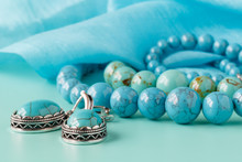Strings Of Turquoise Beads On Blue Silk As A Background