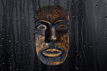 Brown Wood Mask On A Black Background, Through A Drop Of Water