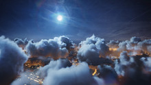 Flying Over The Deep Night Timelapse Clouds With Moon Light. Seamlessly Looped Animation. Flight Through Moving Cloudscape Over Night City Lights. Perfect For Cinema, Background, Digital Composition.