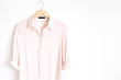 Front view of beauty trendy pink female blouse on hanger near white background. Fashion concept.