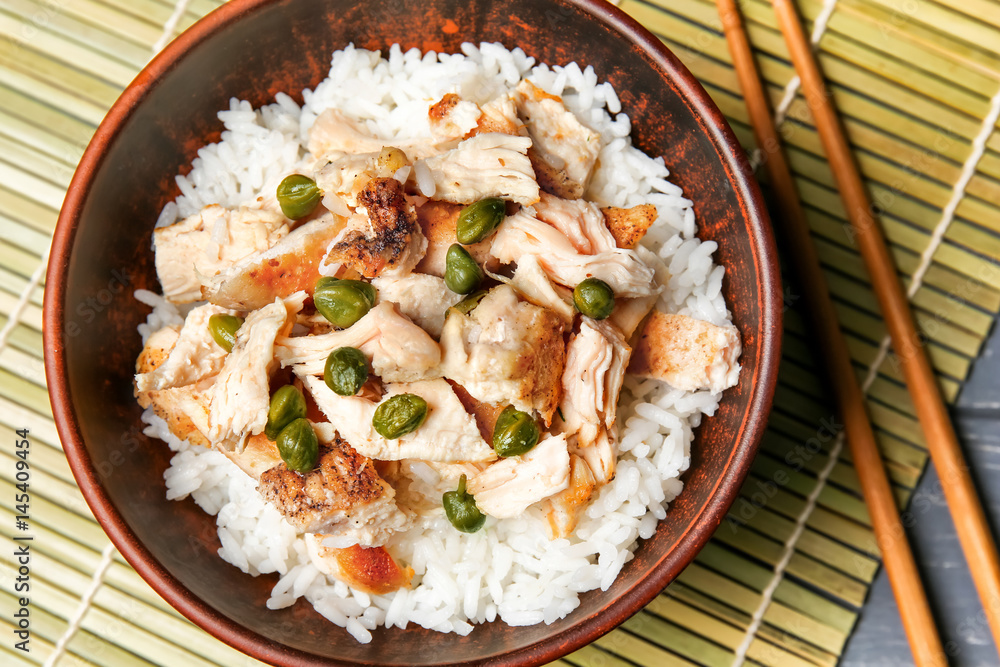 Bowl with chicken and rice on wicker mat