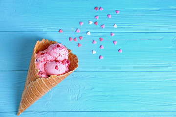 Poster - Delicious ice cream in waffle cone with sprinkles on wooden background