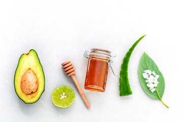 Homemade skin care and body scrub with natural ingredients fresh  avocado , leaves ,sea salt , lime and honey on marble background  with flat lay.