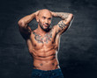 © Fxquadro - Shaved head, muscular male with tattoos on his torso over grey vignette background.