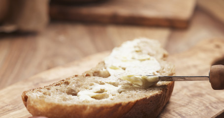 Wall Mural - female teen hand spreads butter on slice of rustic bread, 4k photo