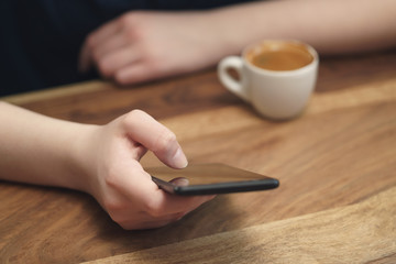 Wall Mural - young female teen hand using smatphone sitting at the table closeup, shallow focus