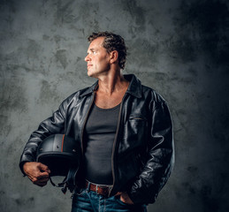 A man holds motorcycle helmet over grey background.