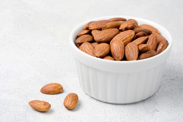 Wall Mural - Almonds in white bowl on grey concrete background