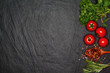 Fresh basil and cherry tomatoes on the dark background with spices. Top view with copy space.