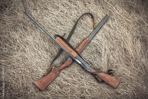 Zdjęcie XXL Skrzyżował polowań pistolety na suchej trawie na haystack jako łowiecki tło
