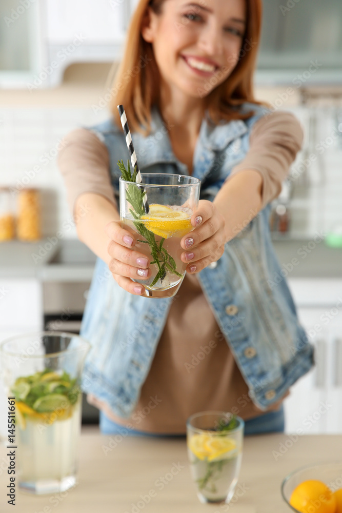 Beautiful young woman with lemonade in kitchen