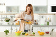 © Africa Studio - Beautiful young woman preparing lemonade in kitchen